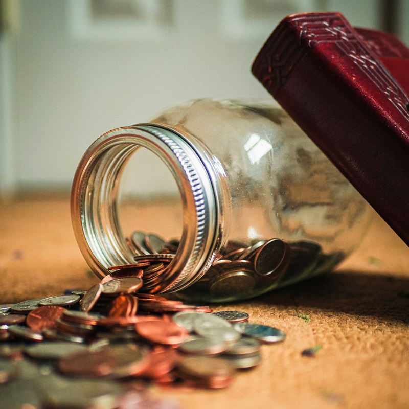 Litigation costs. A money jar on its side with coins spilling out of it