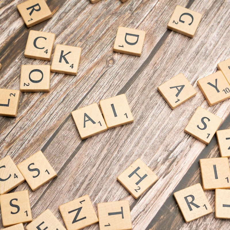 Scrabble tiles spelling out AI on a wooden table.